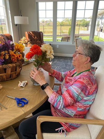 Resident arranging artificial flowers in a bright room