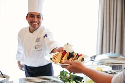 Chef serving a delicious plate of waffles with toppings