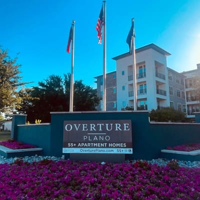 Exterior view of Overture Plano Apartment Homes with flowers and flags
