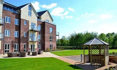 Exterior view of a senior living facility with gardens and seating