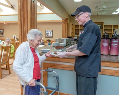 Staff serving food to a resident in the dining area