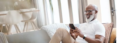 Senior man using smartphone in a cozy living room