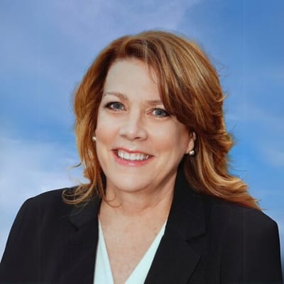 Professional woman smiling in front of a blue sky.