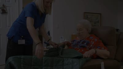 Staff assisting a resident with a blanket.