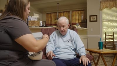 Caregiver assisting a resident in a living room.