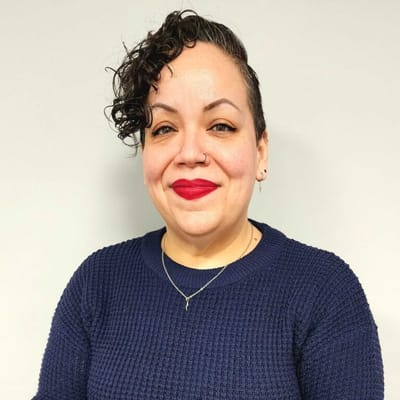 A smiling staff member with curly hair