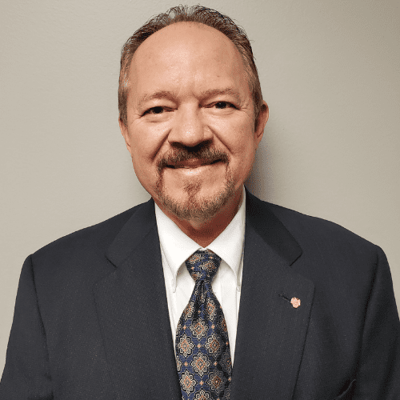 A man in a suit smiling at the camera.