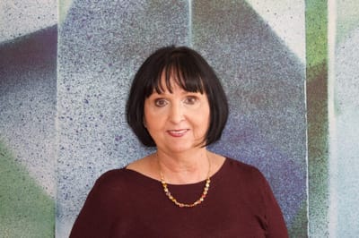 Woman posing in front of a colorful wall.