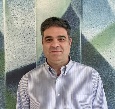 A man standing in front of an abstract wall mural.