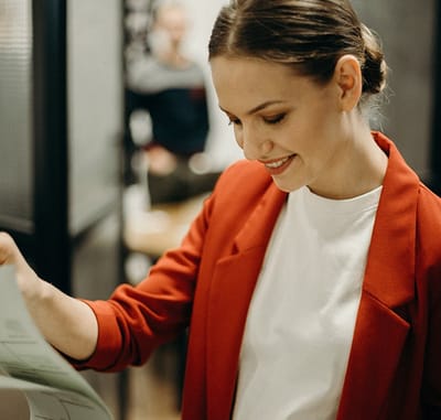 Woman in a red blazer examining a document.