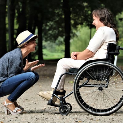 Two women interacting joyfully outdoors in a park setting.