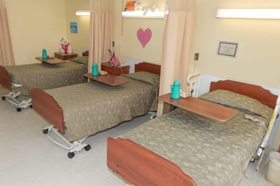 Interior of a resident room with three beds and amenities