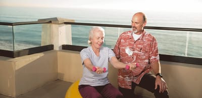 Senior resident exercising with weights outdoors