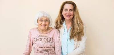 An elderly woman smiling with a caregiver