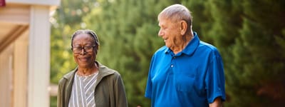 Two residents walking outdoors in a garden area