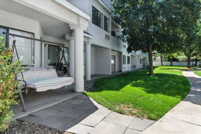 Outdoor patio area with swing and grass