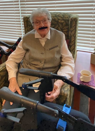 Senior resident sitting in a chair with a playful expression.