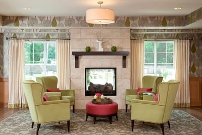 Cozy common area with green chairs and a fireplace