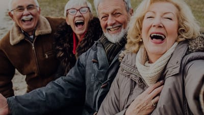 Four seniors joyfully laughing in a group selfie