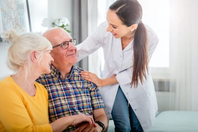Caregiver interacting with two residents in a cozy room