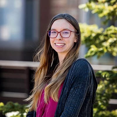 A young staff member smiling outdoors in the community