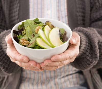 Close-up of hands holding a bowl of salad