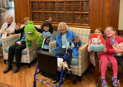 Residents enjoying a social moment with children and plush toys.