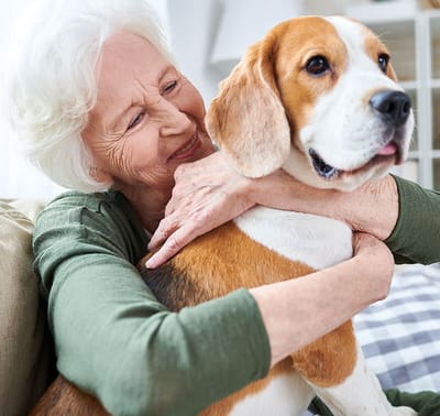Senior woman hugging a dog in a cozy setting.