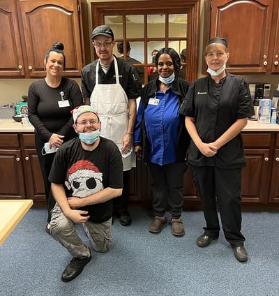 Staff members posing in a facility kitchen.