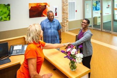 Reception area with staff and visitors interacting.