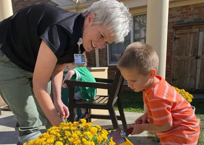Staff member interacting with a child in a garden.