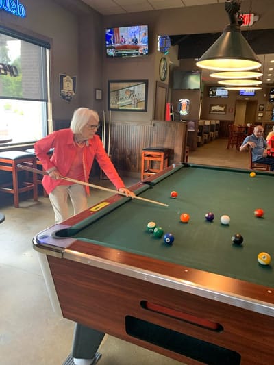 Senior woman playing pool in a social space.