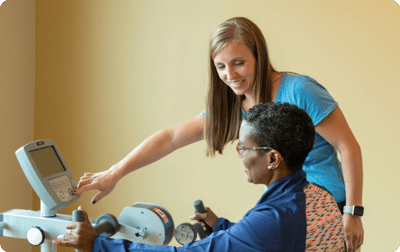 Staff assisting a resident with exercise equipment