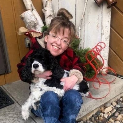 Resident holding a dog outdoors with festive decor.