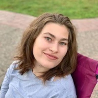 Young woman smiling outdoors in a wheelchair.