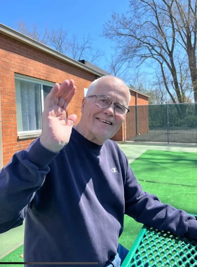 Senior resident waving in an outdoor area