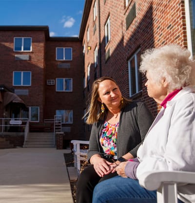 A resident and a staff member chatting outside the facility