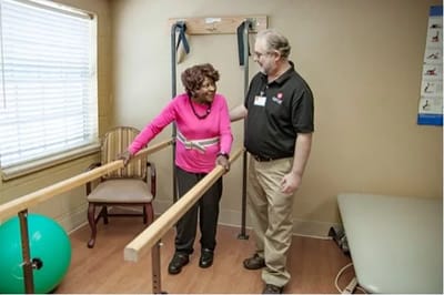 A resident and staff member in a physical therapy room