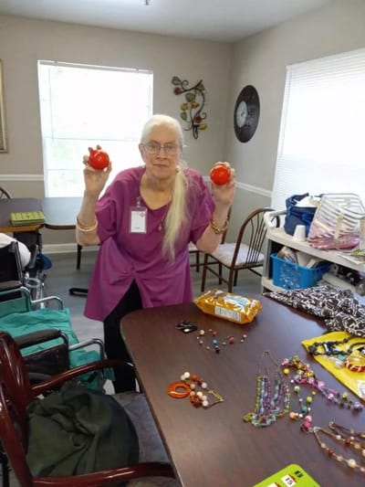 Caregivers of Pleasant Grove, Nursing Home in Pleasant Grove, AL — Senior resident holding two red objects in activity room
