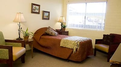 A cozy resident room with a bed and plants