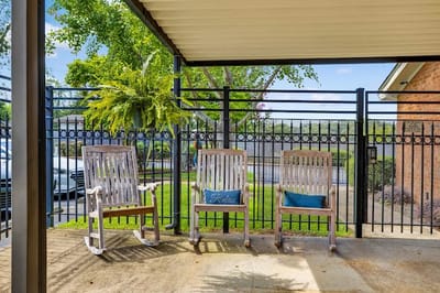 Outdoor seating area with rocking chairs and greenery