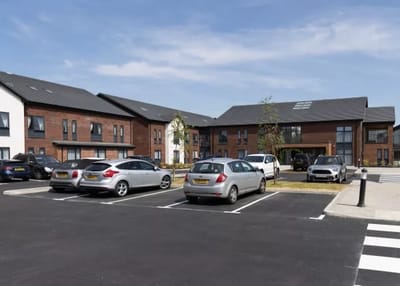 Exterior view of Windmill Lodge Care Home with vehicles