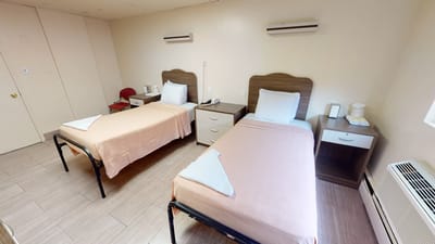 A clean, well-furnished resident room with two beds