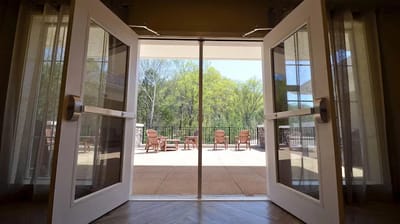 Double doors leading to a sunny outdoor patio area