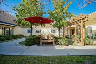 Outdoor seating area with shaded bench and landscaping