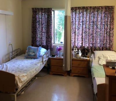 A shared resident room with two beds and curtains