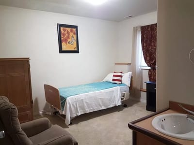 A cozy resident room with a bed, chair, and decor