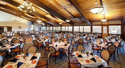 Spacious dining room set for a meal with tables and chairs.