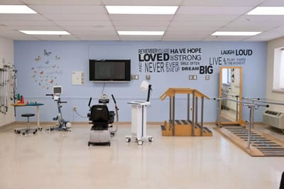 Physical therapy room with equipment and motivational wall art
