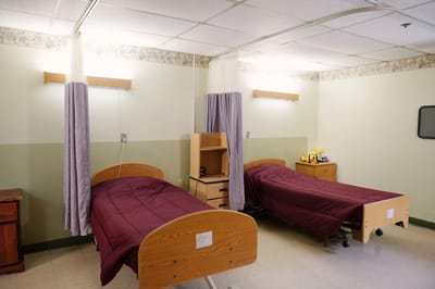 Two hospital-style beds in a shared resident room